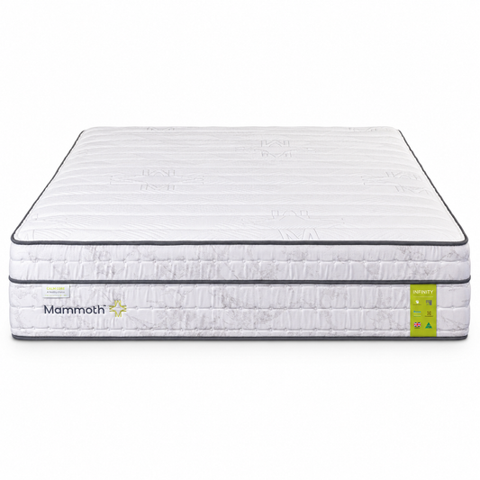 A side-view shot of a Mammoth mattress on a solid white background, showing its quilted white top, textured side panel, black piping, and a green and white size/feature label on the right side.