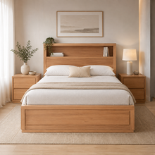 Load image into Gallery viewer, A light oak wood platform bed with a built-in headboard shelf, styled with white bedding and a beige throw blanket, flanked by matching nightstands with lamps and a vase of greenery.