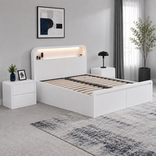 Load image into Gallery viewer, A modern white platform bed frame with an integrated headboard shelf and warm LED lighting, shown in a styled bedroom setting with matching nightstands, a rug, and wall art.