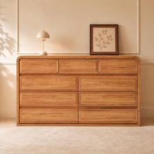 Load image into Gallery viewer, An oak dresser with 9 drawers, rounded corners and seamless handles. Set in a warm bedroom complimented with neutral colours. The dresser has three smaller drawers on the top, with 6 bigger drawers at the bottom in a 2x3 pattern.